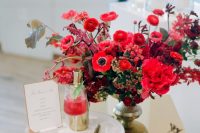 a super bold Christmas wedding centerpiece of a gold bowl, red, fuchsia and burgundy blooms and some foliage is amazing