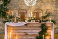 a sweetheart wedding table covered with wood, with a fabric table runner, candles, an evergreen runner and blooms is a lovely idea