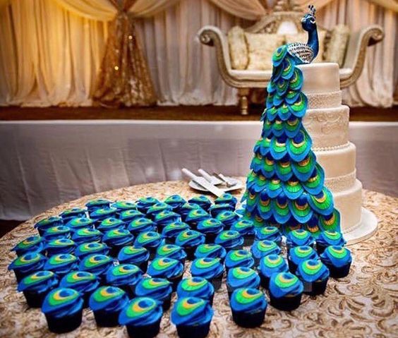a wedding backdrop with a sugar peacock on top and matching cupcakes that form its tail