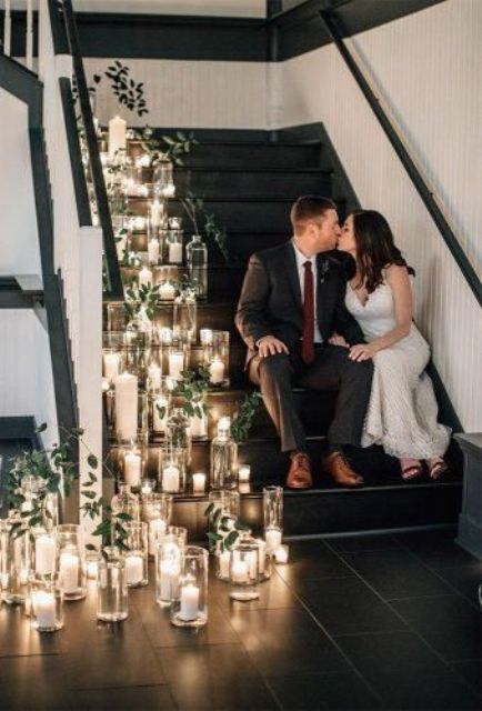 a wedding staircase decorated with lots of candles in jars and some greenery is a cool wedding decor idea to rock