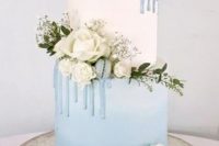a white and ice blue winter wedding cake with baby’s breath, white blooms and blue macarons