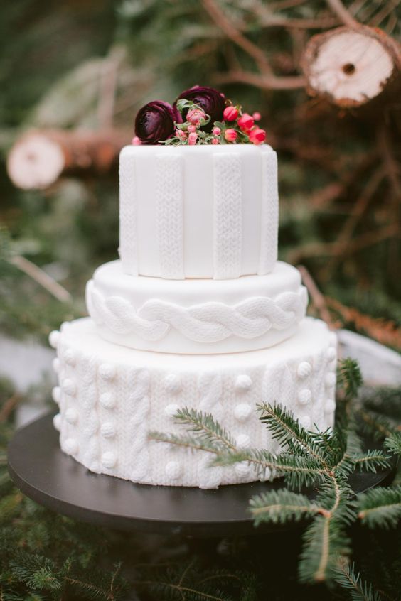a white textural knit-inspired wedding cake with berries and dark blooms on top is a pretty Christmassy piece