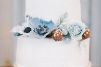 a white wedding cake with ice blue sugar blooms and pinecones is a great idea for a winter wedding