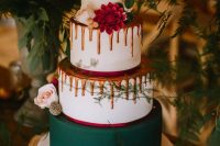 a woodland Christmas wedding cake in white, hunter green and orange, with drip and fresh blooms looks very unusual and modern