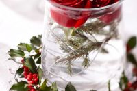 an easy Christmas wedding centerpiece of fir branches, red roses and a berry wreath wrapping the vase