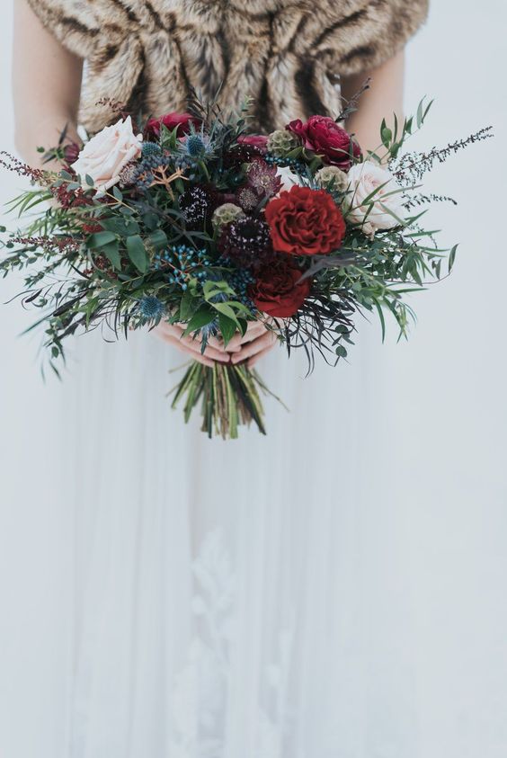an exquisite Christmas wedding bouquet of blush, burgundy and red blooms, thistles, berries and greenery