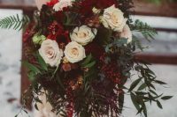 an exquisite Christmas wedding bouquet of white, burgundy blooms, berries and lots of greenery