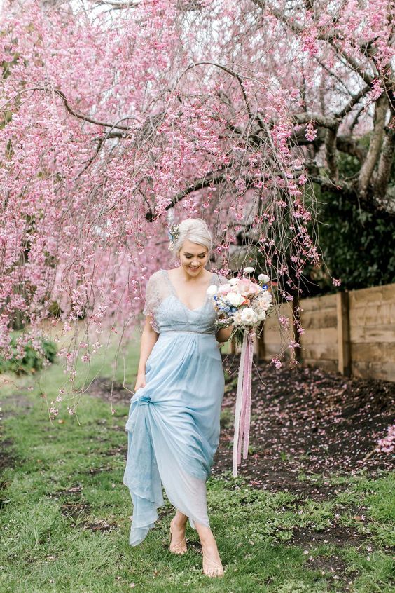 an ice blue wedding dress with a sheer beaded coverup and a deep neckline plus a matching floral headpiece