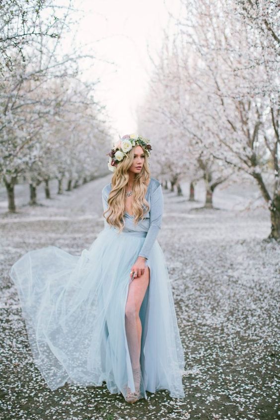 an ice blue winter wedding dress with a shiny long sleeve bodice and a layered skirt with a side slit plus a statement necklace