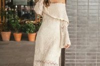 an incredibly romantic off the shoulder crochet maxi wedding dress with a slit, bell sleeves and a tiered neckline for a boho bride
