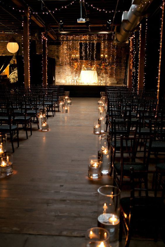 an industrial wedding ceremony space with lights, rows of chairs and floating candles is a stylish space