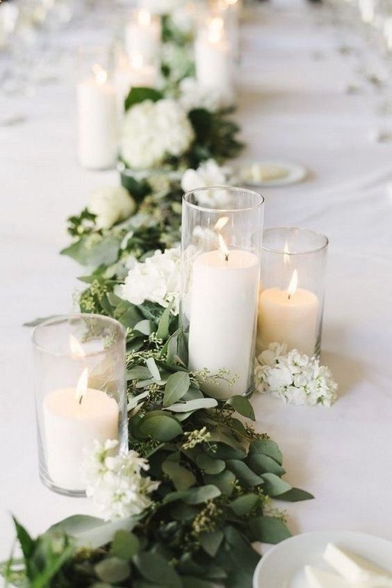 beautiful wedding table decor with greenery, white blooms and pillar candles in glasses is amazing for weddings