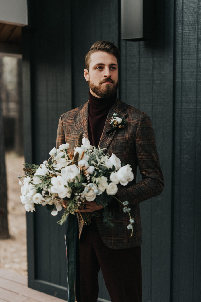 burgundy velvet pants and a matching turtleneck, a brown plaid blazer and a boutonniere for a casual winter groom's look