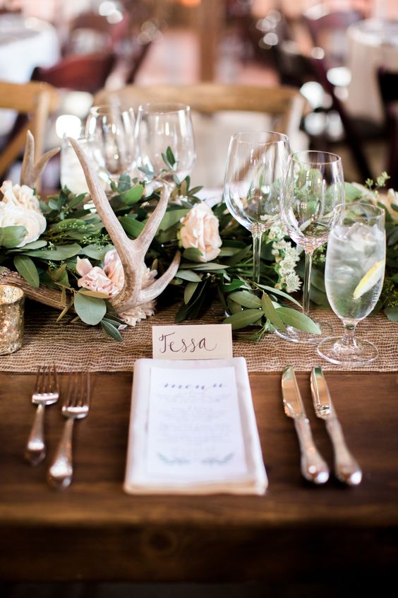 elegant wedding table decor with a greenery and white bloom runner, antlers and a shiny mesh table runner is very chic