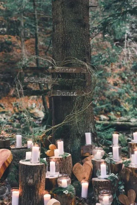gorgeous woodland wedding decor decor of tree stumps with candles, moss and small white blooms plus wooden hearts