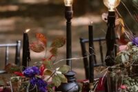 super bold purple blooms, greenery, black candles and bulbs on stands make up a fantastic Halloween wedding centerpiece
