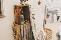 woodland wedding decor of crates, pinecones, cotton, dried leaves, a blanket and antlers on top will fit a fall or winter wedding