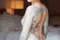 a backless silver sequin wedding dress with long sleeves to show off the bride’s tattoes