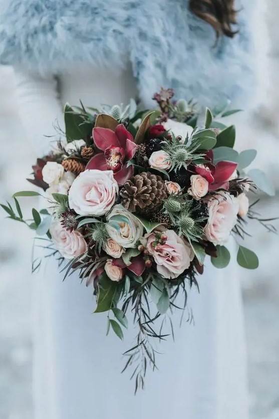 a beautiful pink wedding bouquet of blush and burgundy blooms, greenery, thistles, pinecones is a beautiful idea for both a fall or winter wedding