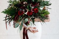 a bold wedding bouquet of burgundy and red blooms, greenery and ferbs, thistles and burgundy ribbons