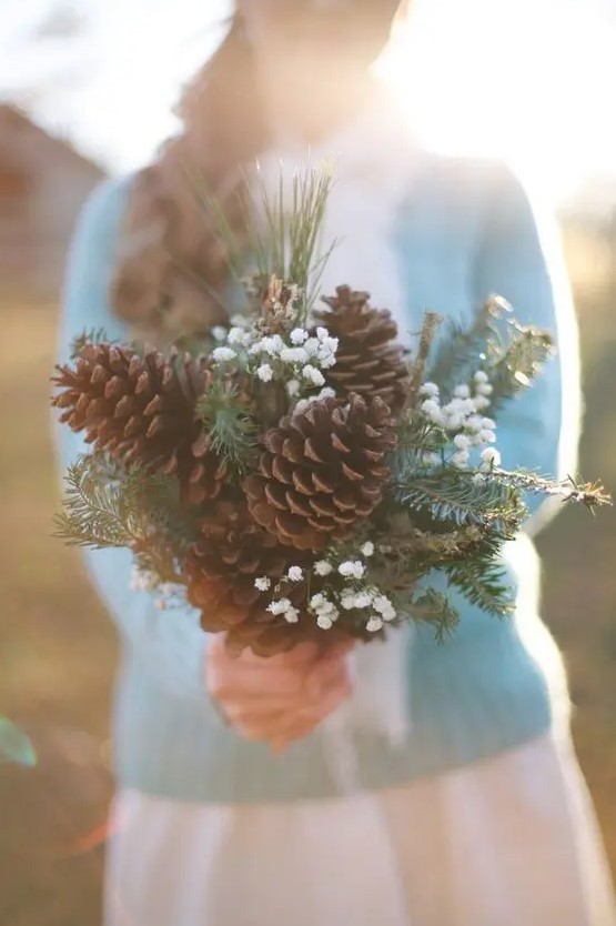 a bouquet made of large pinecones, evergreens and baby's breath for a rustic winter bride