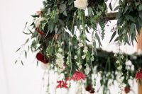 a chic winter wedding chandelier of greenery, white and burgundy blooms, berries and fir for a winter wedding