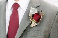 a classic winter wedding boutonniere with berries, usual and gilded ones, a pale leaf and a burgundy rose plus a matching tie