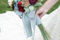 a cool wedding bouquet of white, pink, red and purple blooms of felt, leaves and berries, dusty blue ribbons
