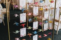 a creative and colorful wedding seating plan with bright printed paper and colorful origami cranes is a lovely idea