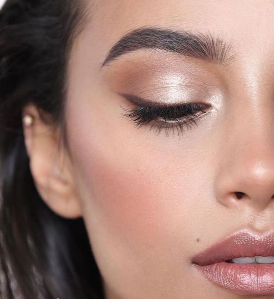 a fresh and catchy wedding makeup with a glossy pink lip, silver eyeshadow, wings and blush, highlighter
