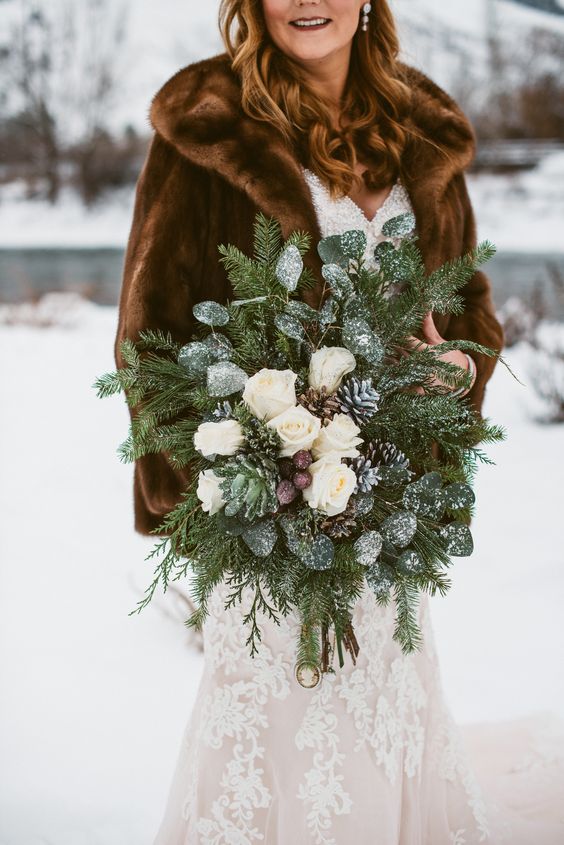 a frozen winter wedding bouquet of evergreens and snowy greenery, white blooms and snowy pinecones is a great idea for a rustic wedding