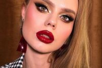 a glam Christmas makeup with a glossy red lip, bold pink blush, gold metallic eyeshadow and lash extensions