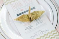 a glam wedding place setting done in blush and gold glitter, with a printed menu and a gold glitter origami crane is cool