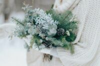 a greenery winter wedding bouquet with evergreens, pinecones and some white blooms is a great idea for a winter bride
