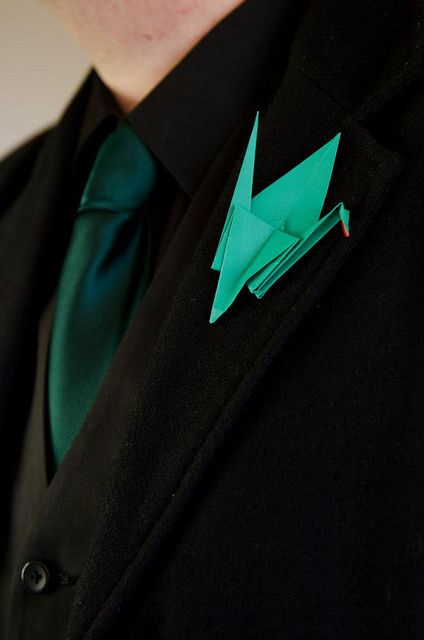 a groom's look with a black suit, black shirt, a green tie and an emerdal origami boutonniere is a lovely and bold idea