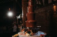 a lovely wedding chocolate fountain bar with various cookies, waffles, fruits and donuts is an amazing alternative to a usual dessert station