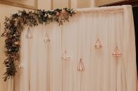 a neutral curtain backdrop with greenery, pastel blooms and rose gold candle lanterns is very romantic and beautiful