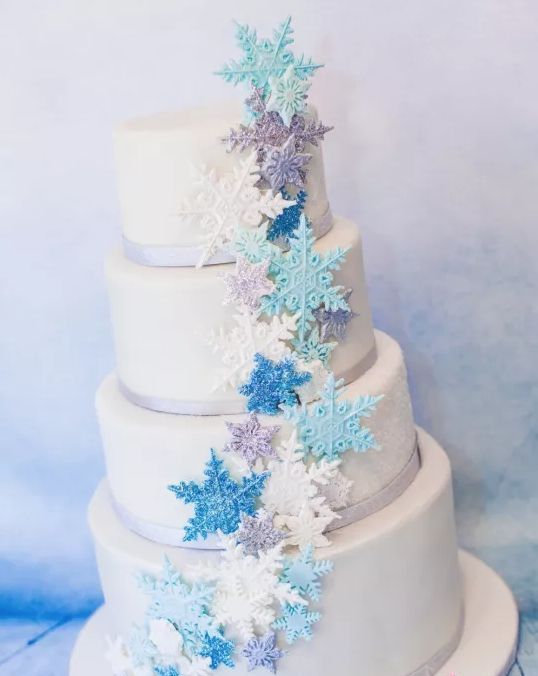 a neutral wedding cake with lilac ribbon, white, turquoise, blue and lilac snowflakes is a chic and bold idea for winter
