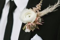 a neutral winter wedding boutonniere of a white bloom and pink ones, dried herbs and blush blooms