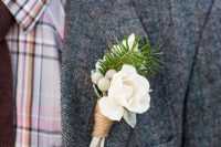a neutral winter wedding boutonniere of white blooms, neutral berries, fir and twine wrapping