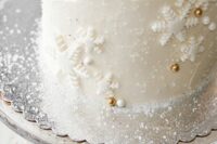 a neutral winter wedding cake decorated with sugar snowflakes, beads and pearls and some sugar imitating frost