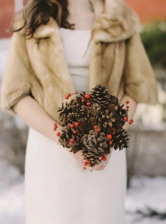 a pinecone and red berries small wedding bouquet for a cool rustic winter flavor