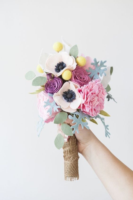 a pink felt flower wedding bouquet with billy balls, leaves and a burlap wrap is a stylish idea for spring or summer