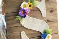 a plaque with a felt monogram, with bright felt blooms and leaves is a cool rustic decoration for a wedding