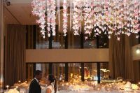 a refined neutral wedding reception space with lots of blooms and garlands of pink origami cranes and crystals over the dancing floor