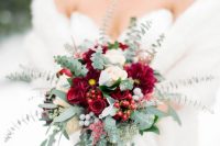 a refined winter wedding bouquet of burgundy and white blooms, berries and greenery for a winter bride