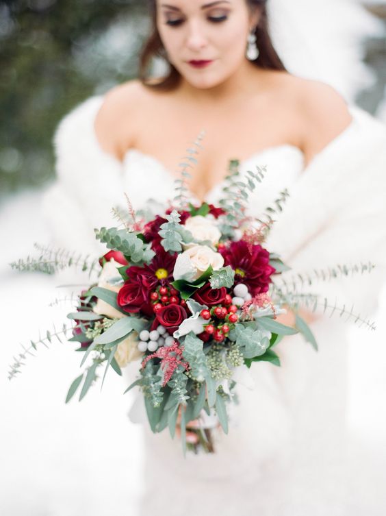 a refined winter wedding bouquet of burgundy and white blooms, berries and greenery for a winter bride