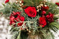 a romantic Christmas wedding bouquet of greenery and fir, gilded berries, red and burgundy blooms