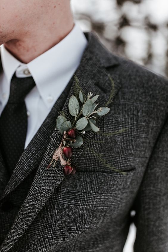 a rustic winter wedding boutonniere of berries, greenery and with a twine wrap for a boho look