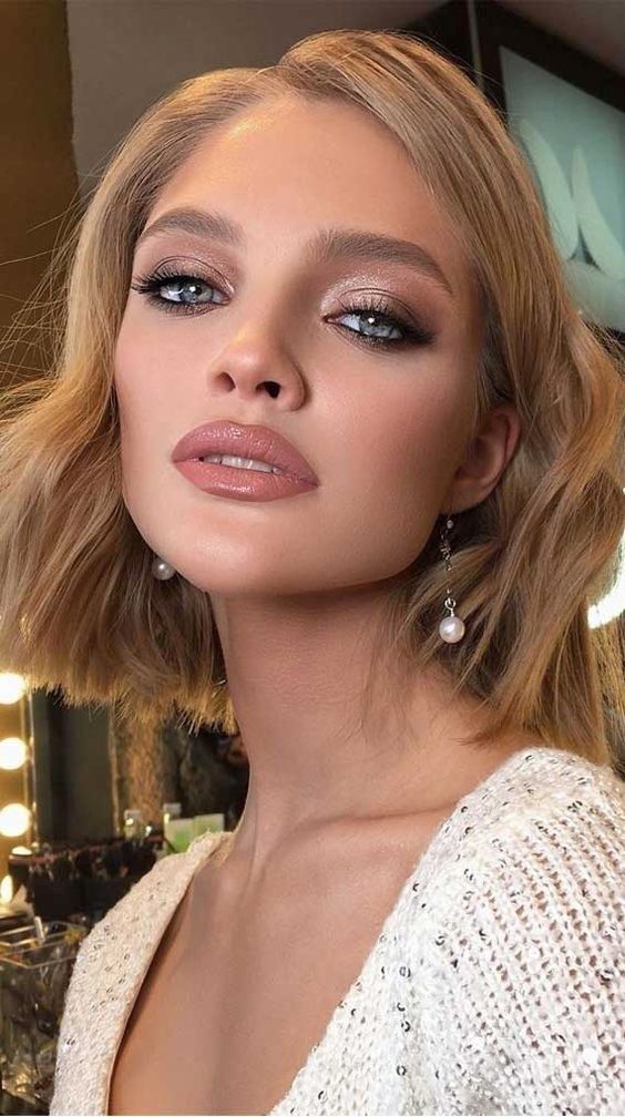a shiny holiday makeup with a glossy nude lip, silver eyeshadow, a touch of blush and perfect tone